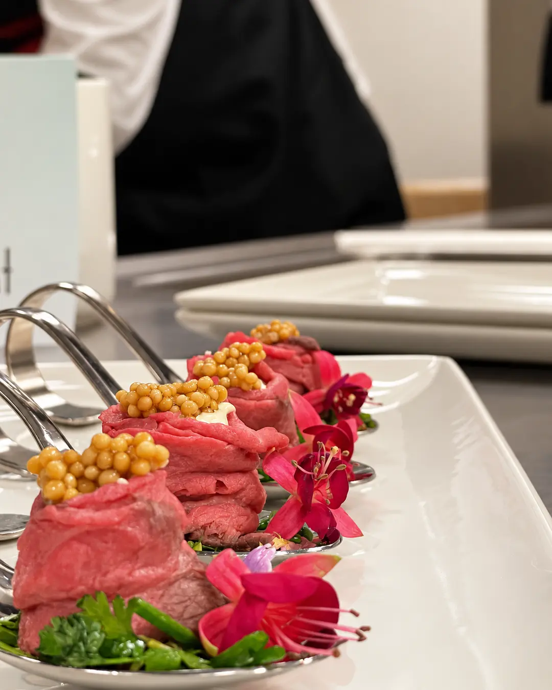 Rinder-Fingerfood auf Löffeln mit essbaren Blüten