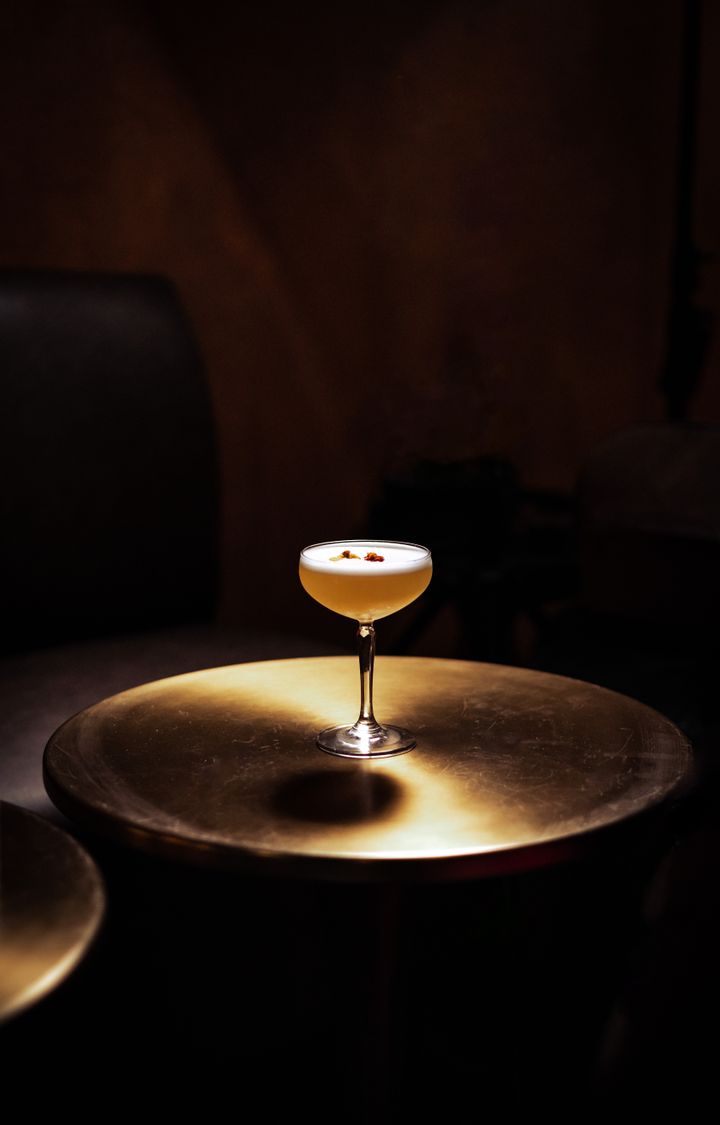 Goldener Cocktail in einem Coupette-Glas bei warmem Licht