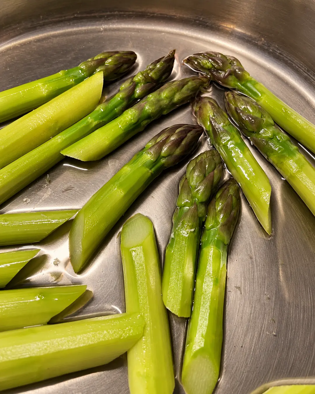 Grüner Spargel in einer Edelstahlpfanne bei der Vorbereitung